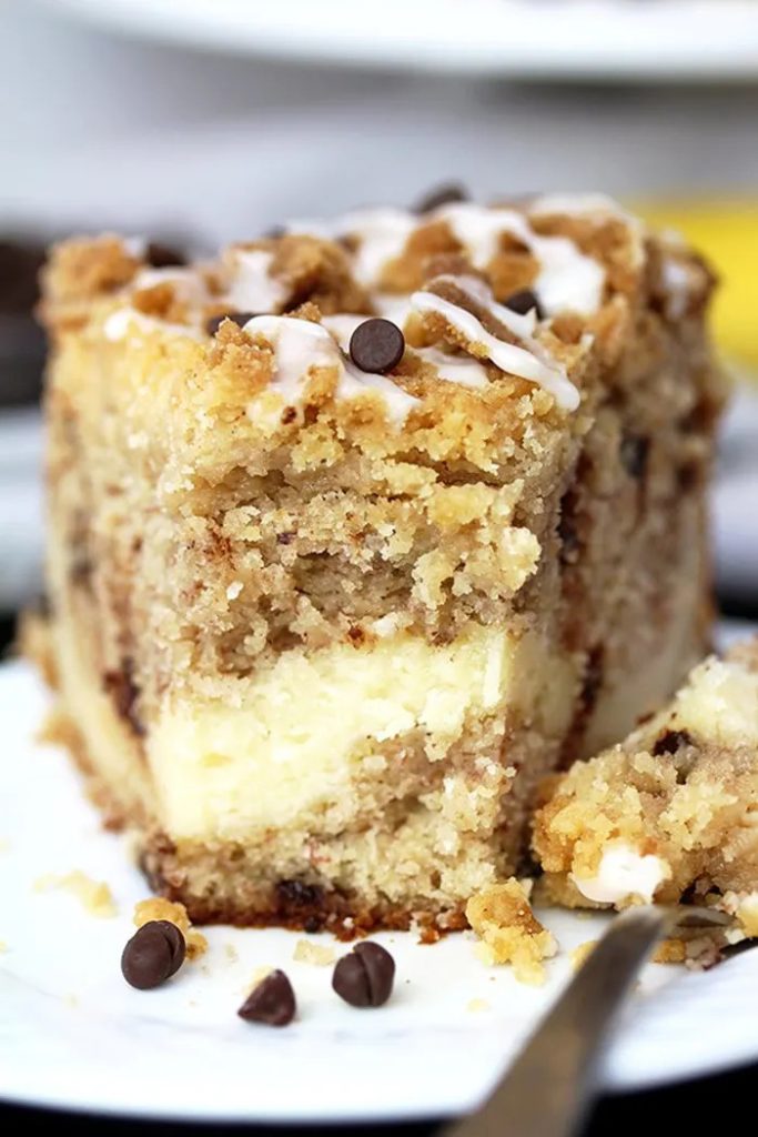 a slice of coffee cake on a dish with a cream center and chocolate chips on top