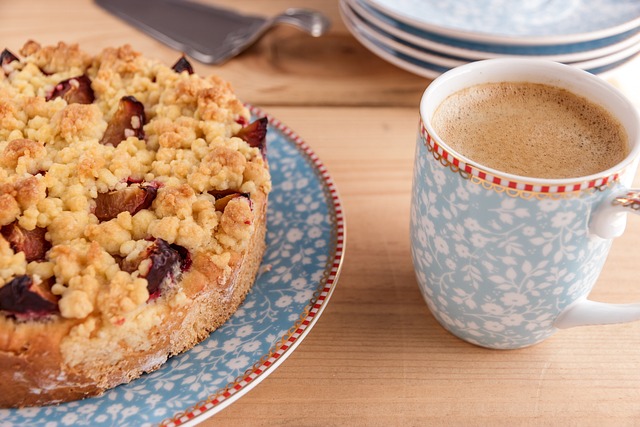A round coffee cake with crumble top on a blue dish with a cup of coffee