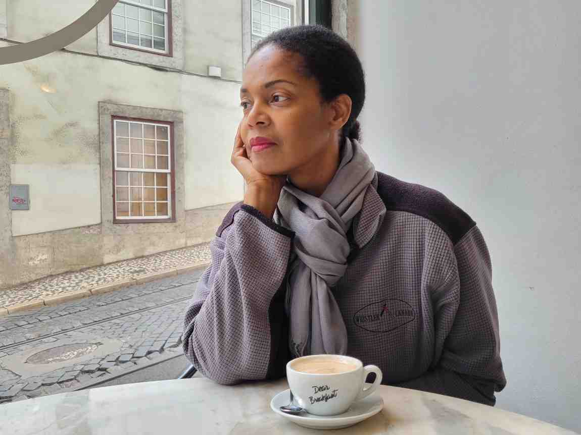 woman looking out a window with a cup of coffee in Lisbon Portugal
