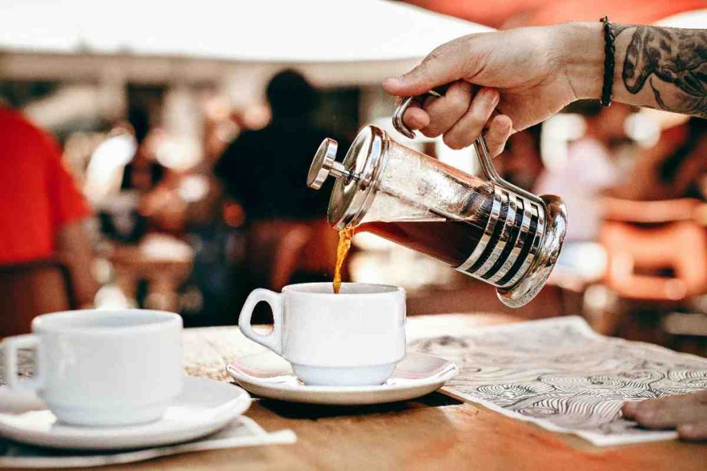 hand pouring coffee into two cups