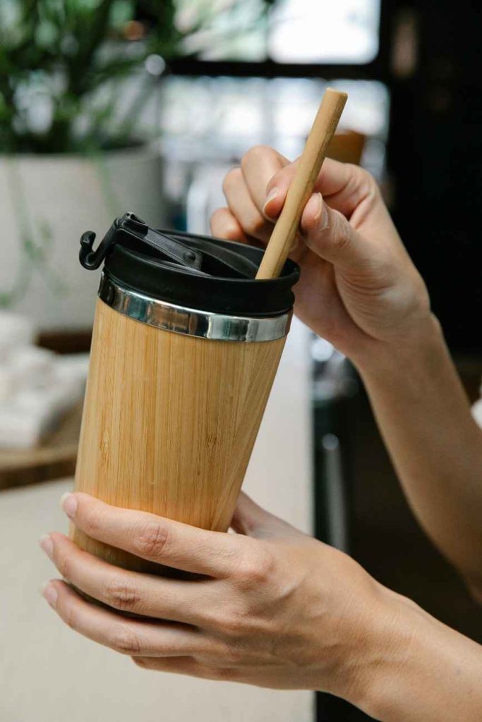 A person holding a wooden style cup
