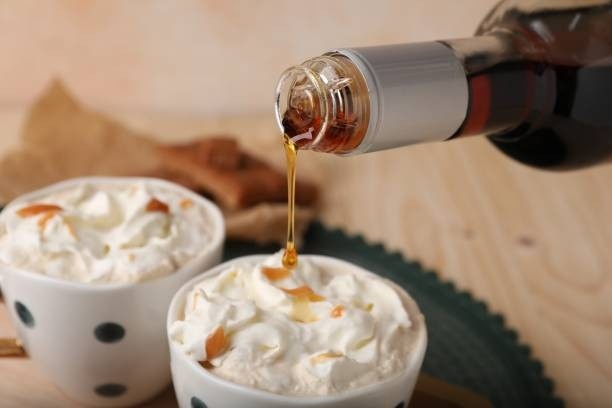 a bottle of syrup dripping over 2 cups of coffee