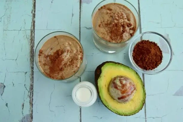 A avocado half and a half of avocado with a Chocolate Avocado Coffee Smoothie
