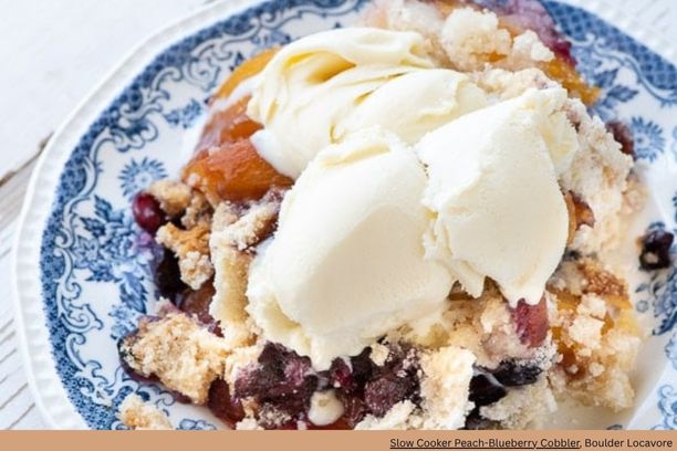 A plate of blueberry and peach cobbler topped with ice cream