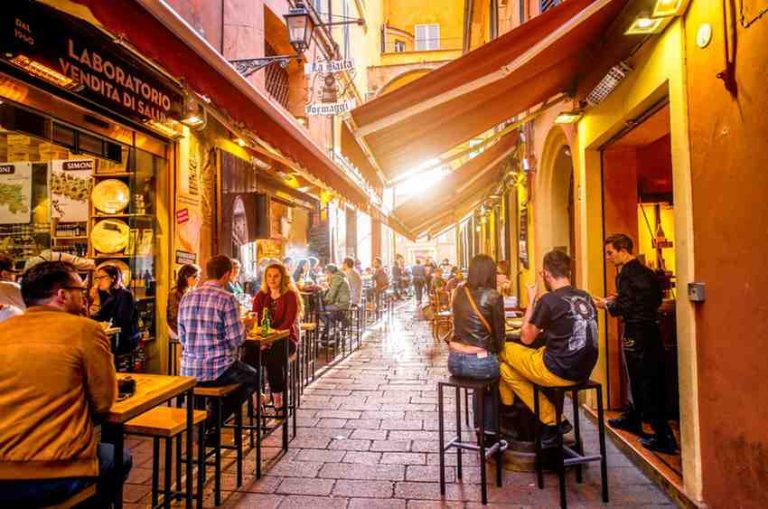 cafe lined street with people sitting outdoors in Bologna