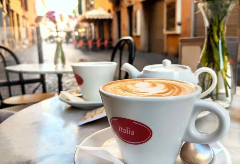 two cups of coffee sitting on a table at an outdoor cafe in Italy