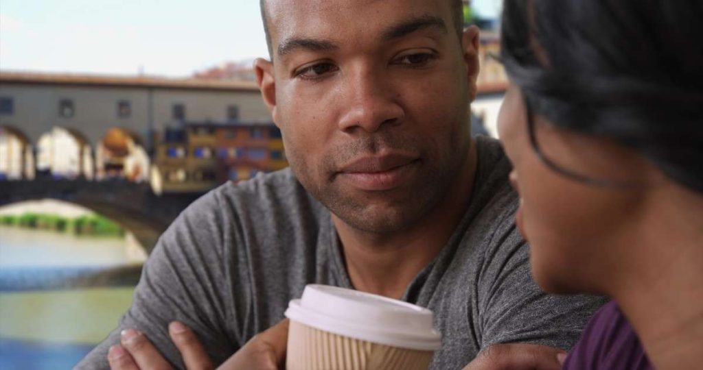 close up of man holding a cup of coffee at a cafe in Florence near the Ponte Vecchio bridge