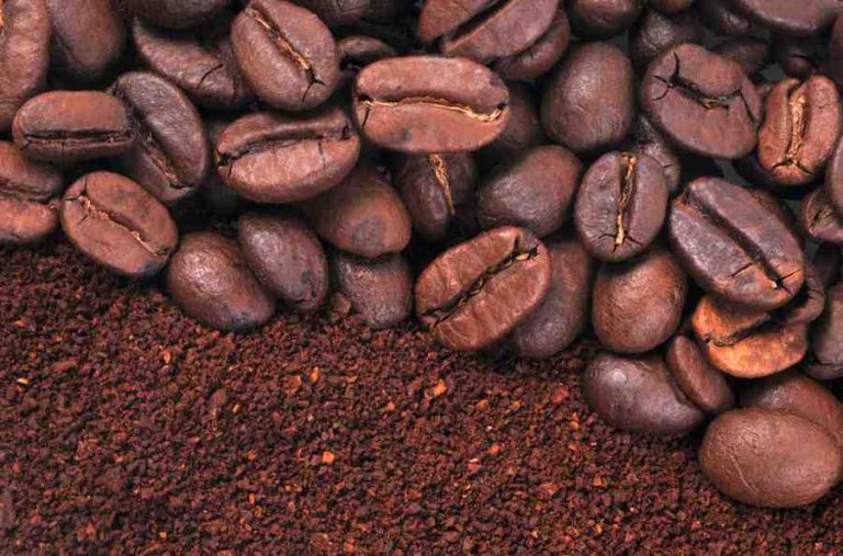 A close-up view of whole roasted coffee beans on the top half of the image, with finely ground coffee filling the bottom half, showing texture and rich brown tones.